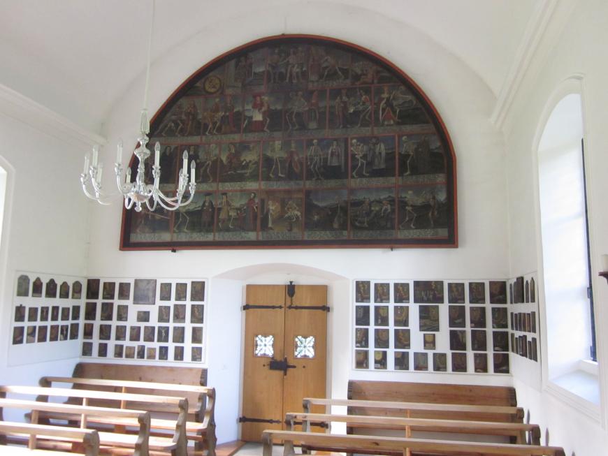 Rückwand der Kapelle mit dem Totentanz und den Votivbildchen